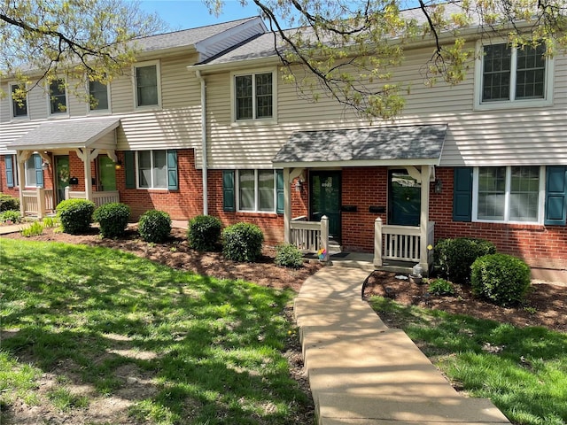 view of front of property featuring brick siding, a porch, and a front lawn