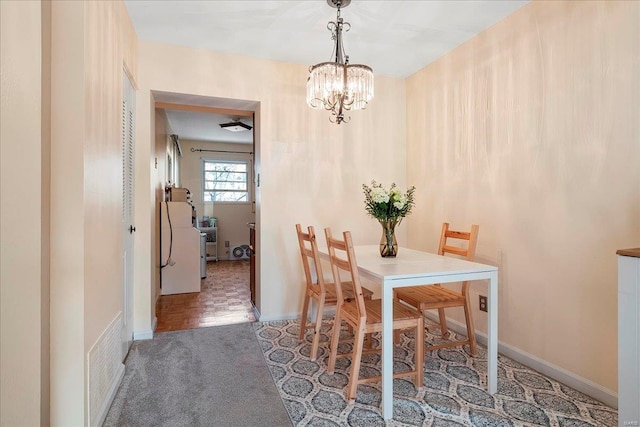 carpeted dining space with baseboards and a chandelier