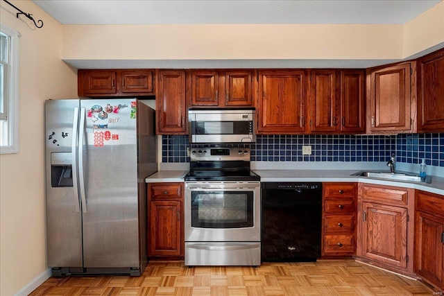 kitchen featuring light countertops, backsplash, appliances with stainless steel finishes, and a sink