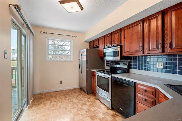 kitchen with brown cabinetry, baseboards, stainless steel appliances, decorative backsplash, and light countertops