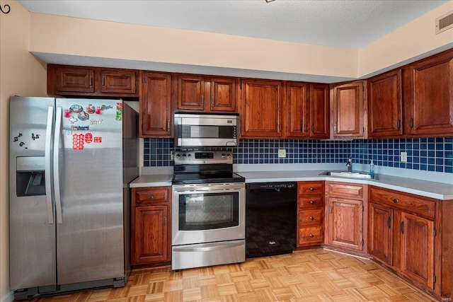 kitchen with decorative backsplash, light countertops, appliances with stainless steel finishes, and a sink