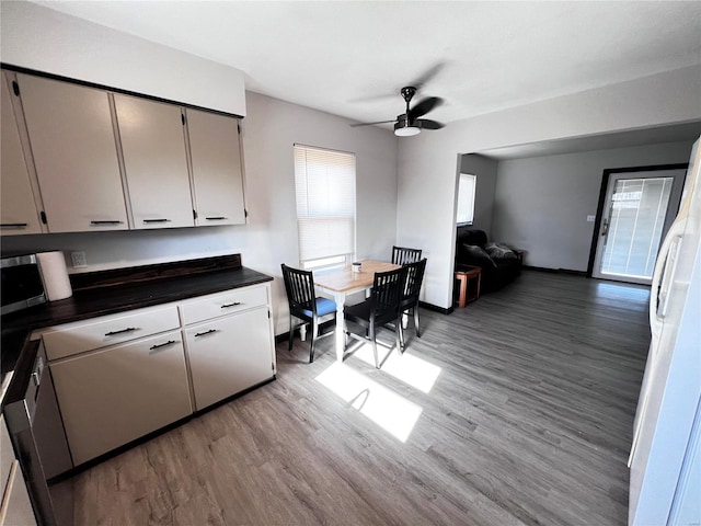 kitchen featuring dark countertops, ceiling fan, open floor plan, freestanding refrigerator, and light wood-style floors