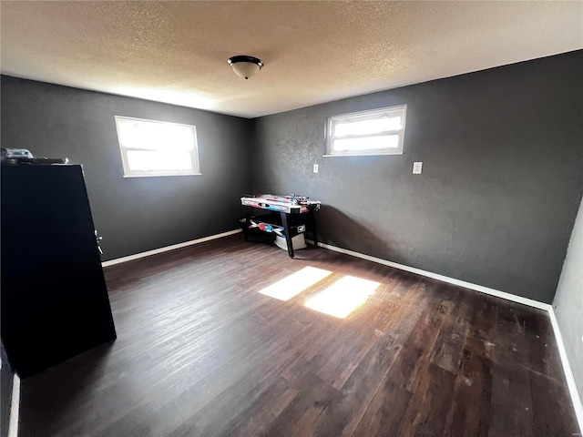 interior space with a textured ceiling, dark wood-type flooring, and baseboards