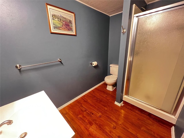 bathroom featuring hardwood / wood-style floors, a textured ceiling, a shower with door, and toilet