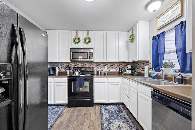 kitchen featuring tasteful backsplash, white cabinetry, sink, and black appliances