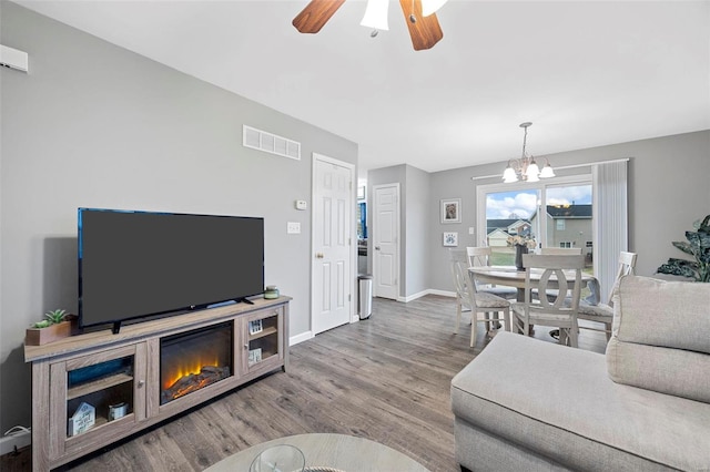 living room featuring wood-type flooring and ceiling fan with notable chandelier