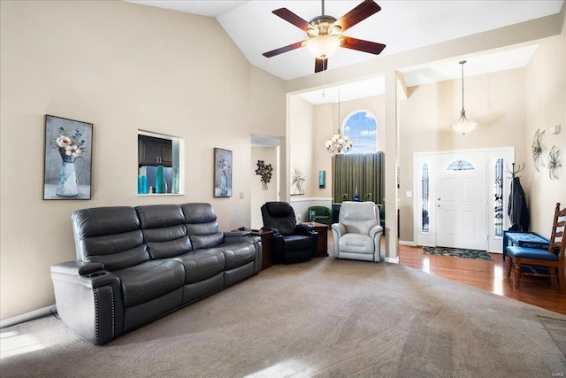 carpeted living room with ceiling fan with notable chandelier and high vaulted ceiling