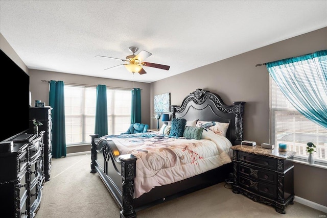 bedroom featuring ceiling fan, light carpet, and a textured ceiling