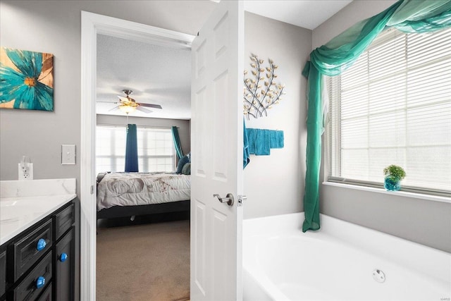 bathroom featuring ceiling fan, vanity, a bathing tub, and a textured ceiling