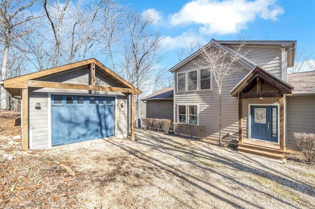 view of front facade featuring entry steps, a detached garage, and driveway