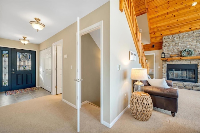 foyer entrance with light carpet, a fireplace, and baseboards