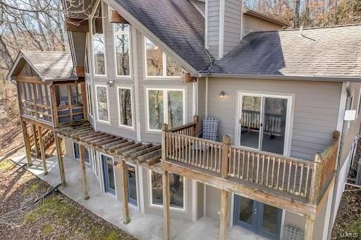 rear view of house featuring a patio, a balcony, a shingled roof, stairway, and a chimney