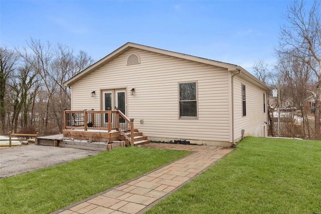 back of house with french doors, a lawn, and a deck