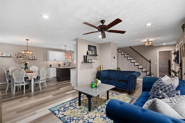 living area featuring recessed lighting, a ceiling fan, light wood-type flooring, baseboards, and stairs