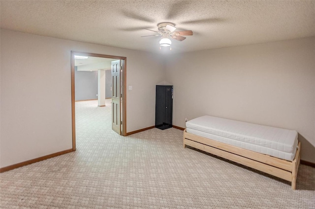 unfurnished bedroom featuring ceiling fan, light colored carpet, and a textured ceiling