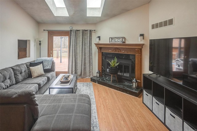 living room with lofted ceiling with skylight, hardwood / wood-style floors, and a high end fireplace