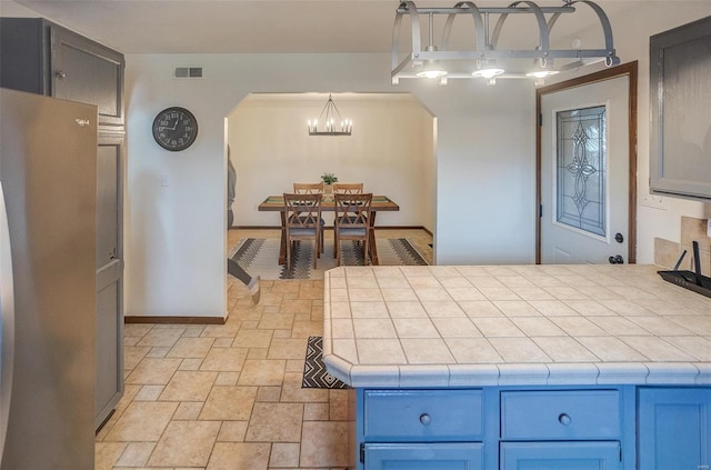 kitchen featuring an inviting chandelier, decorative light fixtures, and tile counters