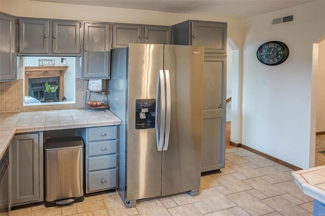 kitchen with decorative backsplash, tile counters, and stainless steel fridge