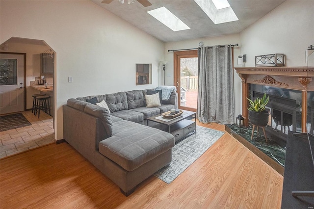 living room featuring hardwood / wood-style floors, high vaulted ceiling, a premium fireplace, and ceiling fan