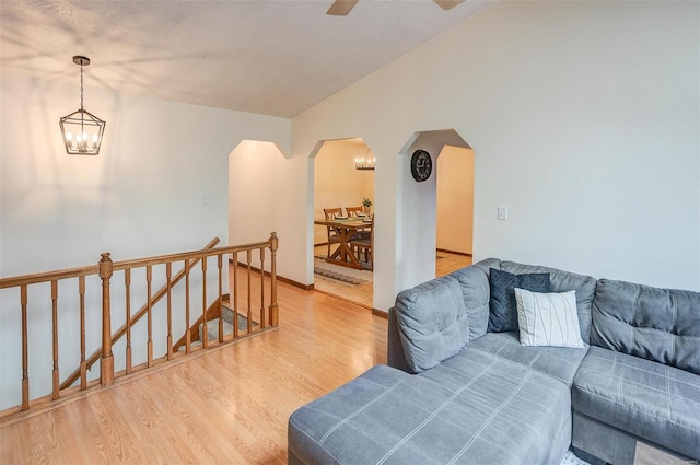 living room with lofted ceiling, ceiling fan with notable chandelier, and light hardwood / wood-style floors