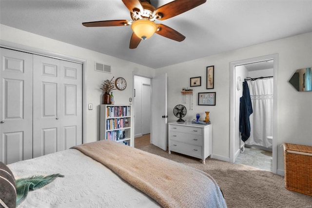 bedroom with ensuite bath, light colored carpet, ceiling fan, and a closet