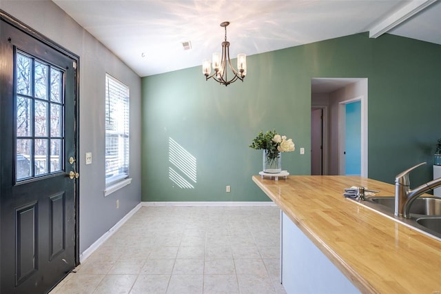 kitchen featuring sink, lofted ceiling with beams, light tile patterned floors, a notable chandelier, and pendant lighting