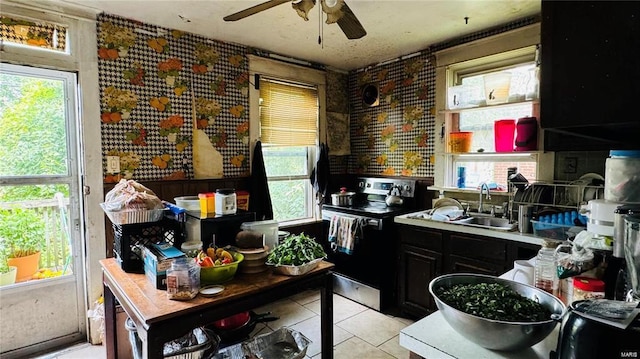 kitchen featuring sink, stainless steel electric range, a wealth of natural light, and light tile patterned flooring