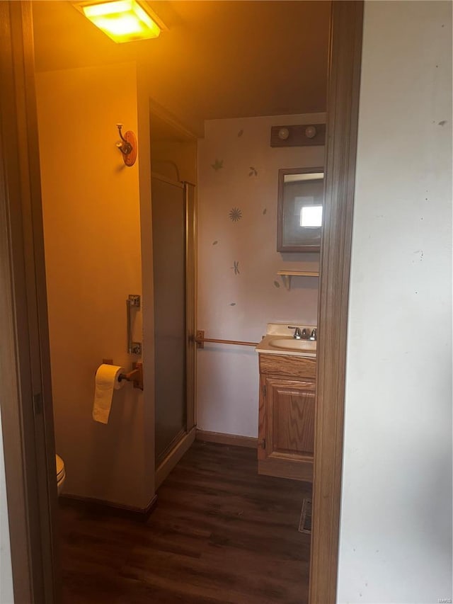 bathroom with vanity, hardwood / wood-style flooring, a shower with shower door, and toilet