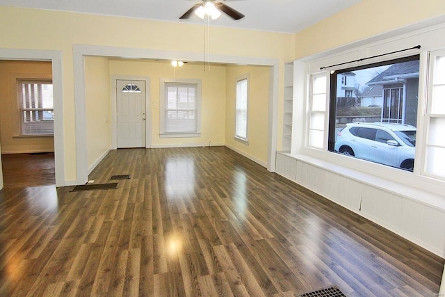 unfurnished living room with dark wood-type flooring, a wealth of natural light, built in features, and ceiling fan