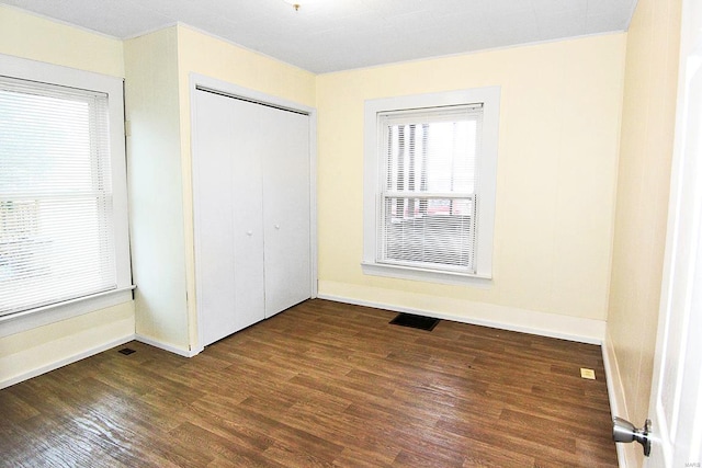 unfurnished bedroom featuring dark hardwood / wood-style flooring and a closet