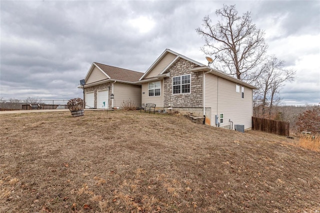 view of front of home featuring cooling unit, a garage, and a front lawn