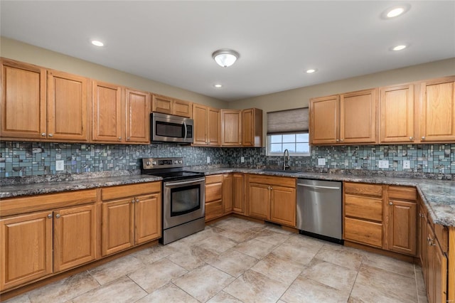 kitchen with sink, backsplash, stainless steel appliances, and dark stone counters