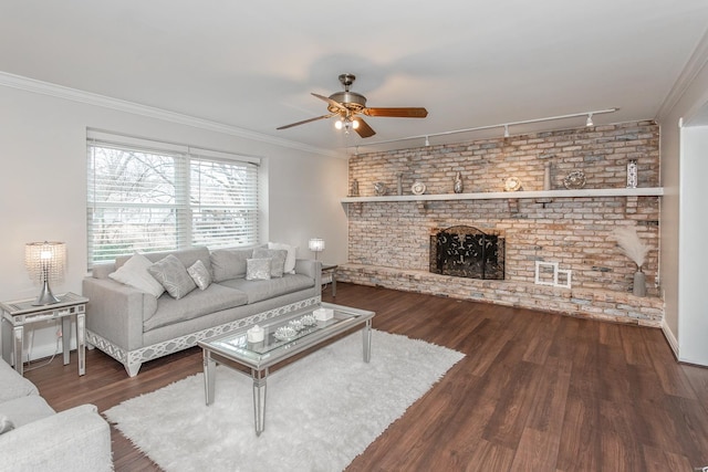 living room with a fireplace, dark hardwood / wood-style flooring, ceiling fan, crown molding, and track lighting