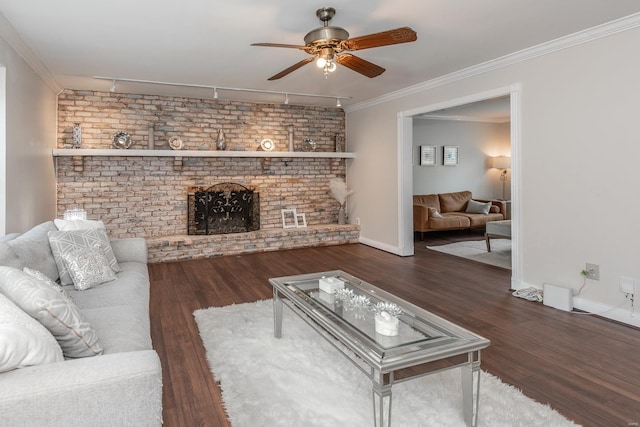 living room with ceiling fan, crown molding, a brick fireplace, dark wood-type flooring, and track lighting