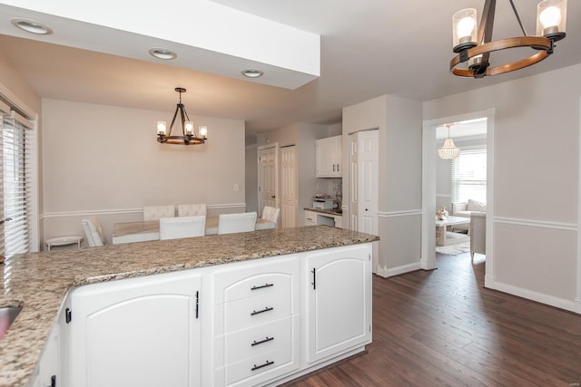 kitchen with an inviting chandelier, decorative light fixtures, dark hardwood / wood-style flooring, and white cabinets