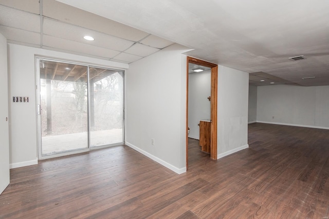 unfurnished room featuring dark hardwood / wood-style flooring and a paneled ceiling