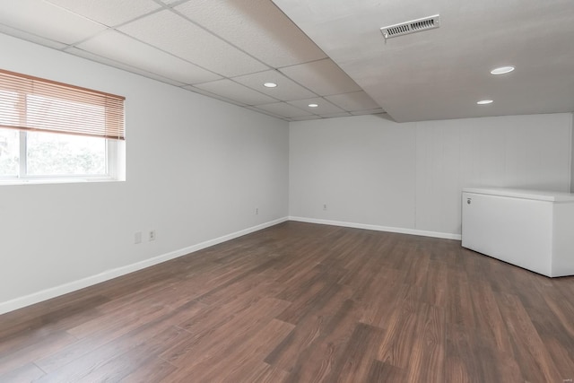 unfurnished room with dark hardwood / wood-style flooring and a paneled ceiling