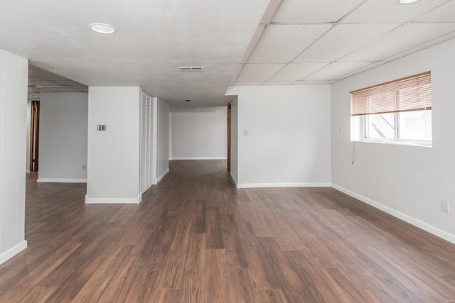 spare room featuring dark wood-type flooring and a paneled ceiling