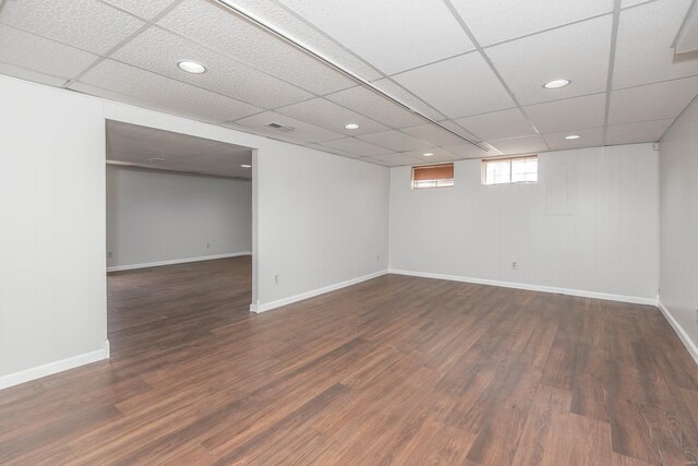 basement with dark hardwood / wood-style flooring and a drop ceiling