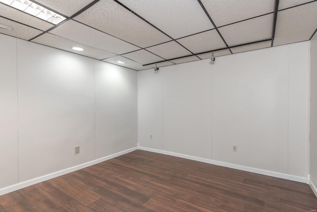 spare room with a drop ceiling and dark wood-type flooring