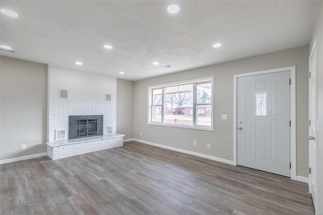 entrance foyer featuring wood-type flooring, a brick fireplace, and a textured ceiling