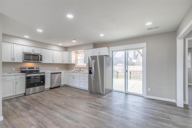 kitchen featuring light wood-type flooring, stainless steel appliances, sink, and white cabinets