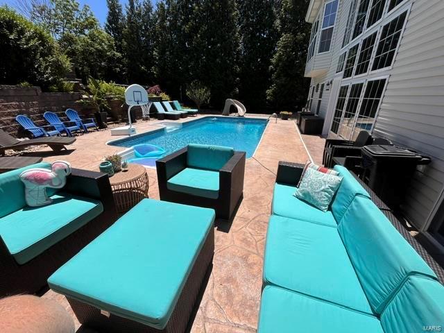 view of pool featuring outdoor lounge area, a patio, and a water slide