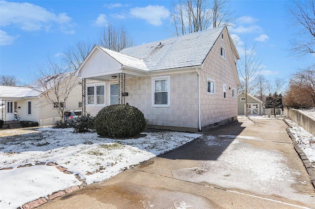 bungalow-style house with an outbuilding, concrete driveway, and a shingled roof