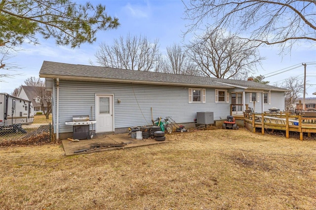 rear view of house with cooling unit, a wooden deck, and a lawn