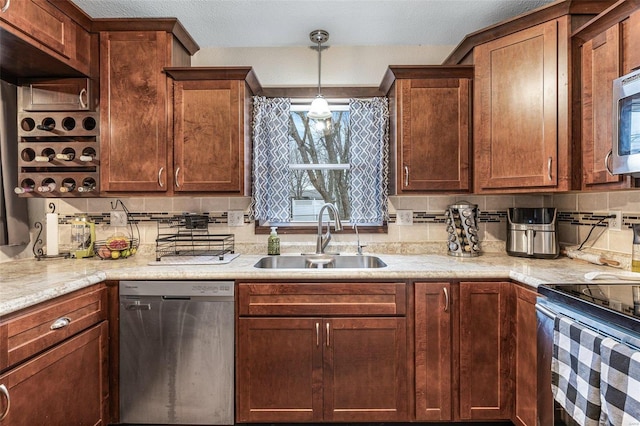 kitchen with sink, appliances with stainless steel finishes, backsplash, light stone countertops, and decorative light fixtures