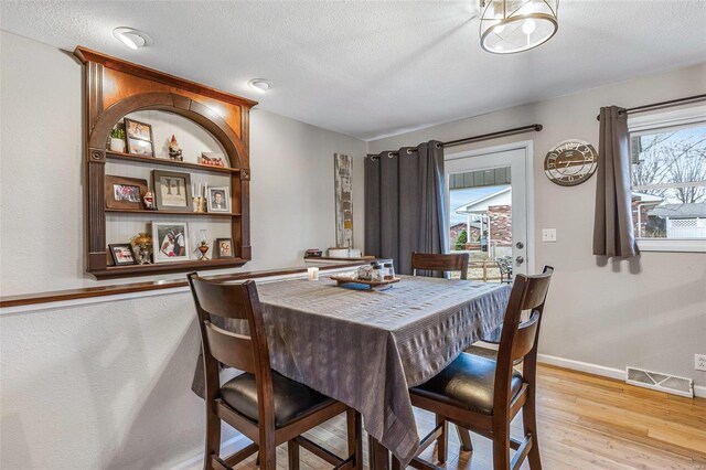 dining room with a textured ceiling and light wood-type flooring