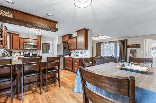 dining area with plenty of natural light, a textured ceiling, ceiling fan, and light hardwood / wood-style flooring