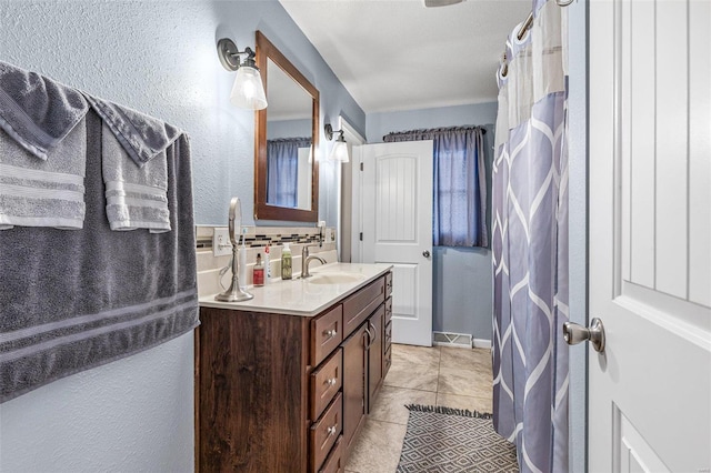 bathroom with tasteful backsplash, vanity, and tile patterned floors