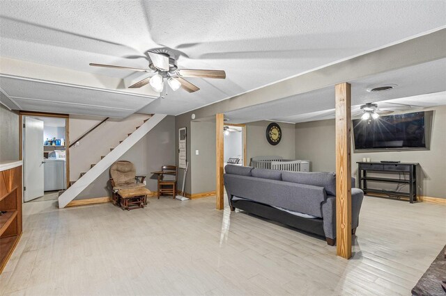 living room with ceiling fan, washer / dryer, light hardwood / wood-style flooring, and a textured ceiling